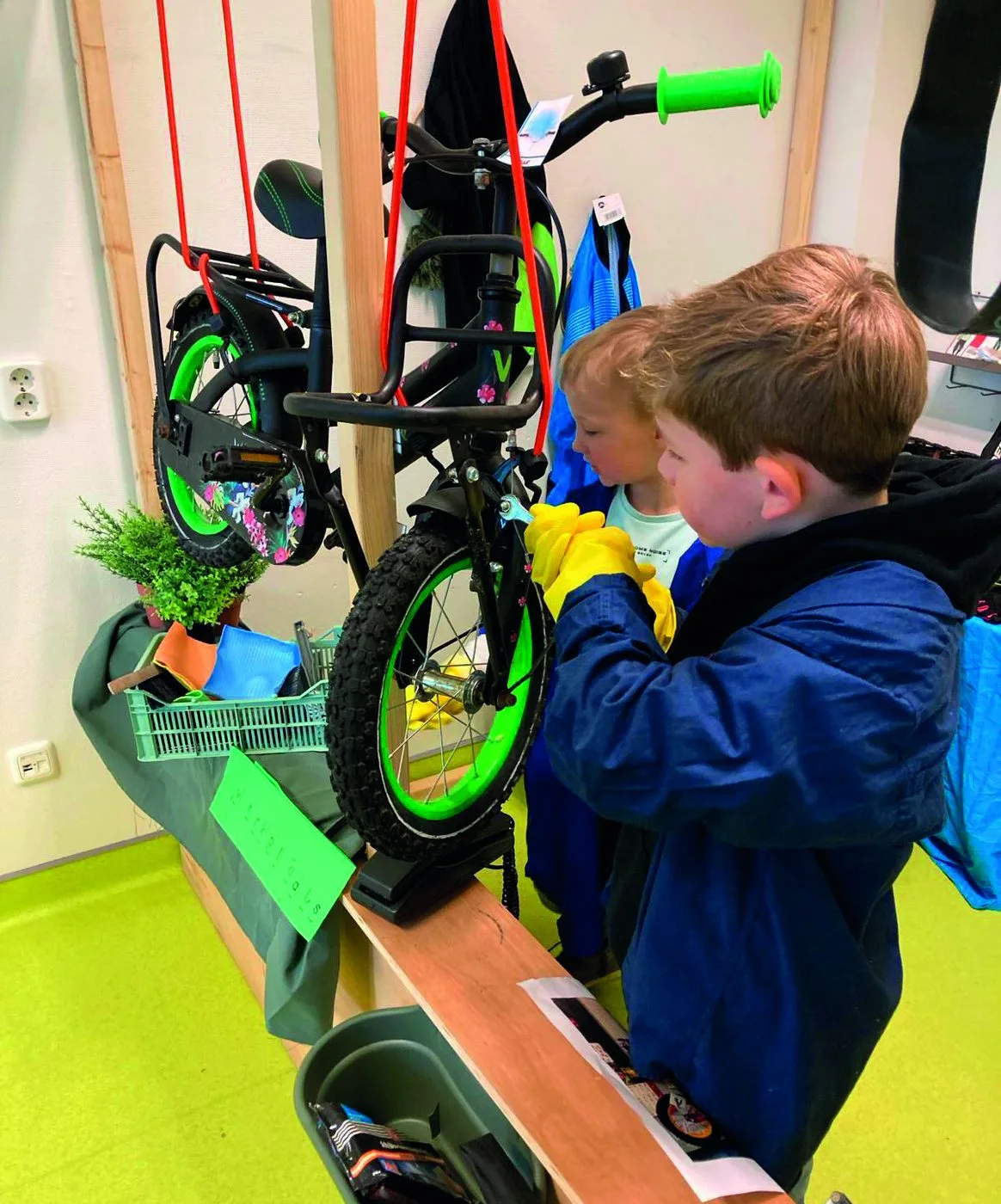 Twee kinderen sleutelen samen aan een fiets in de reparatiehoek