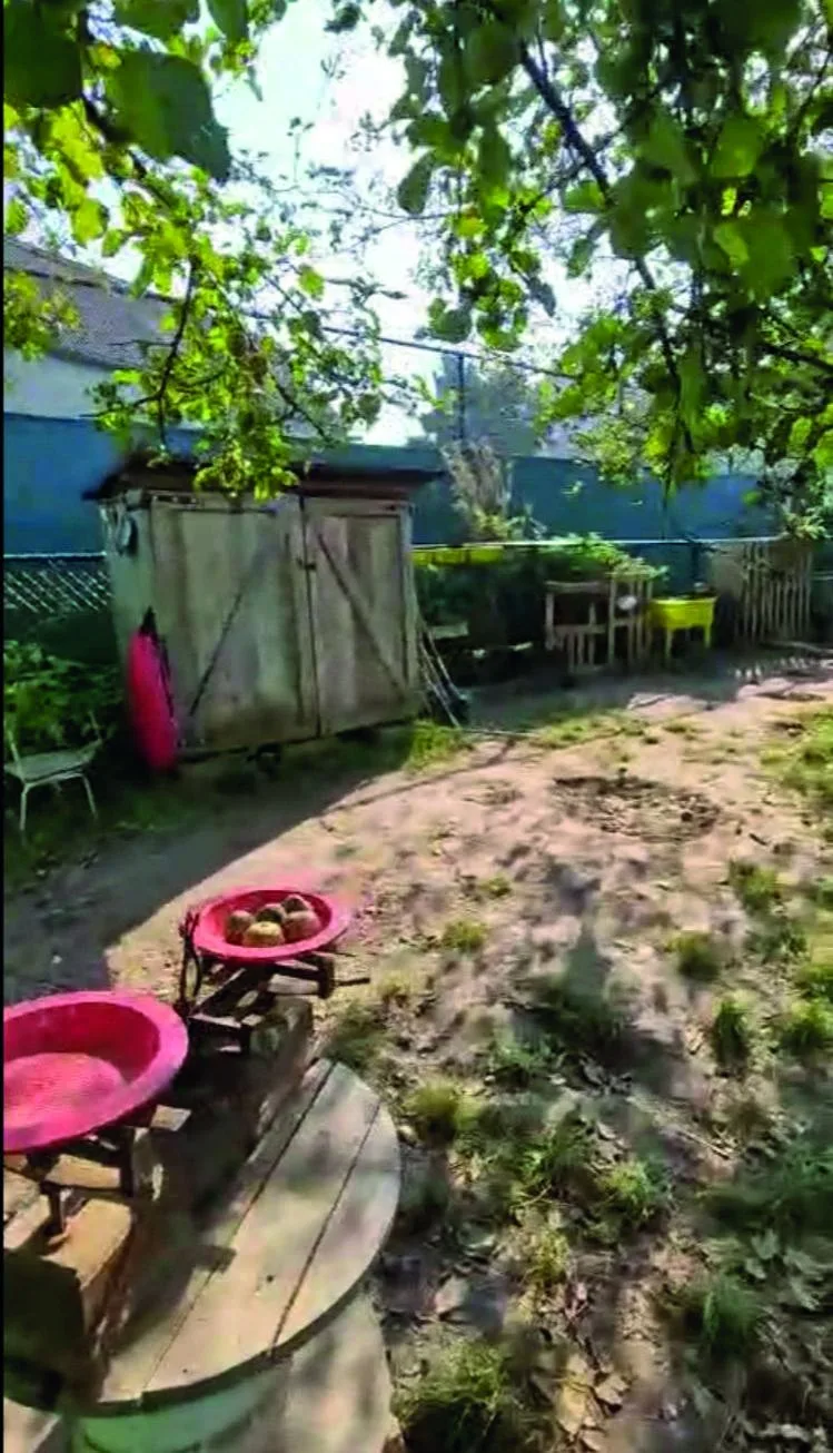 Buitenspeelplek met zand, houten hut en rode teiltjes waar kinderen zelfstandig spelen